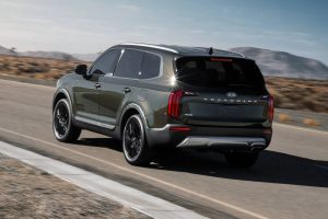 A green 2021 Kia Telluride driving on the highway.