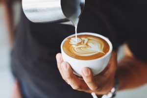 Barista using cream in coffee