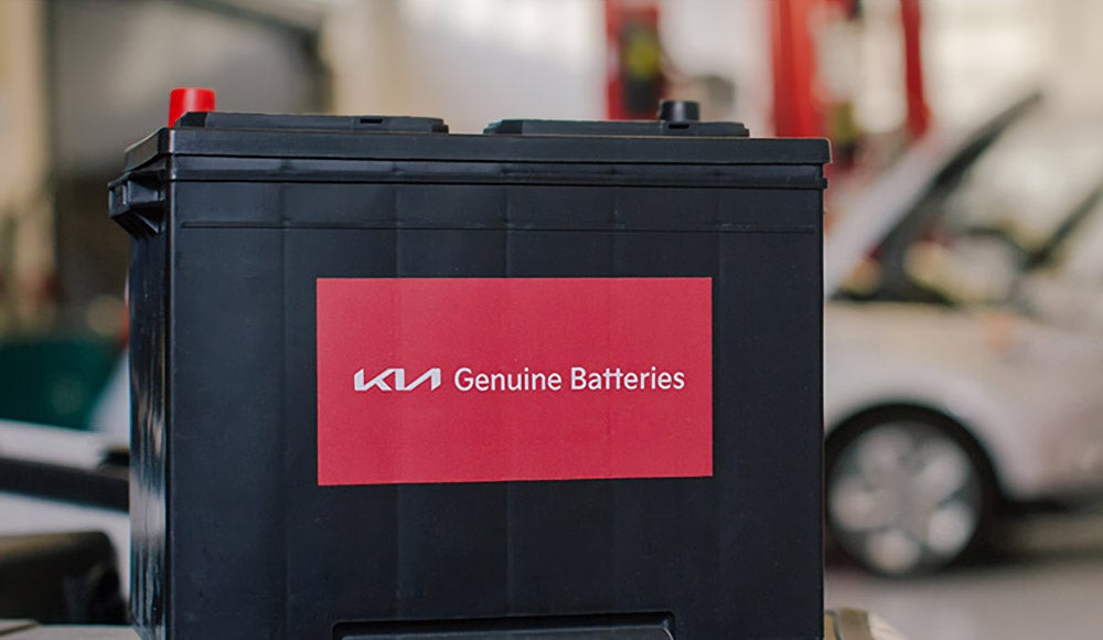 Kia Genuine Battery displayed in an automotive service shop.